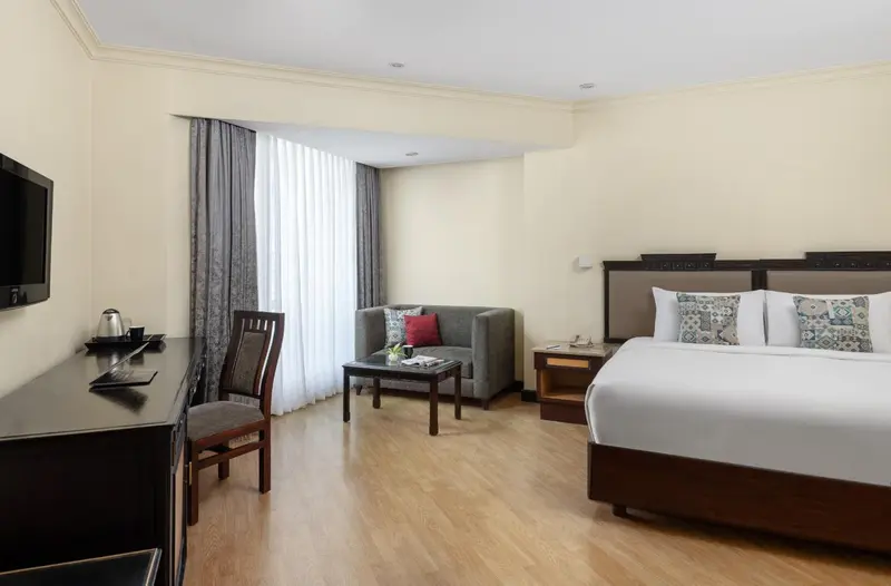 Une chambre lumineuse avec un lit double et un coin salon.