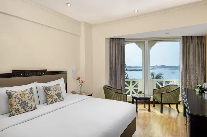 Une chambre lumineuse avec un grand lit et un coin salon donnant sur une vue mer.