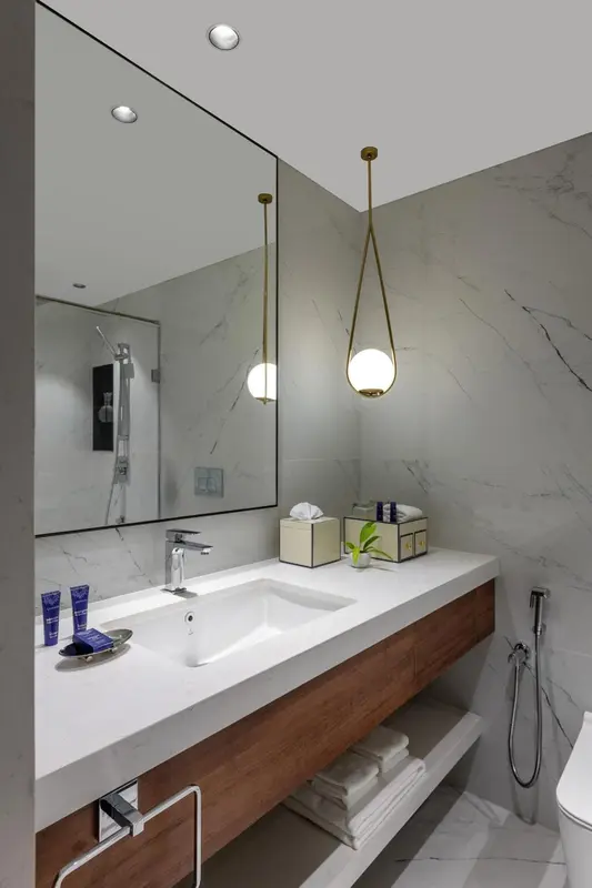 Une salle de bain moderne avec un grand miroir et un plan vasque en marbre.