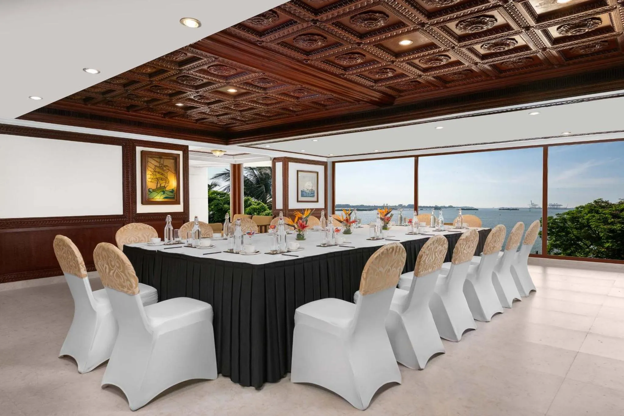 Une longue table de réunion est disposée dans une salle lumineuse avec vue sur la mer.