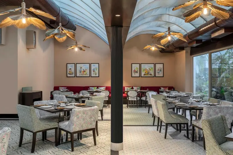 Une salle de restaurant lumineuse avec des tables dressées et des luminaires originaux.