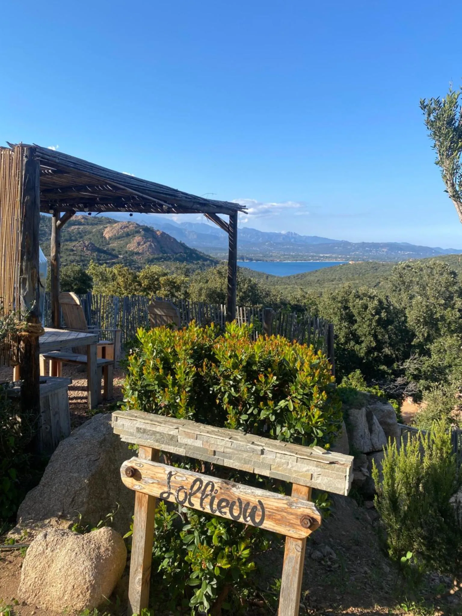 Terrasse ombragée avec vue sur la mer et les collines environnantes.