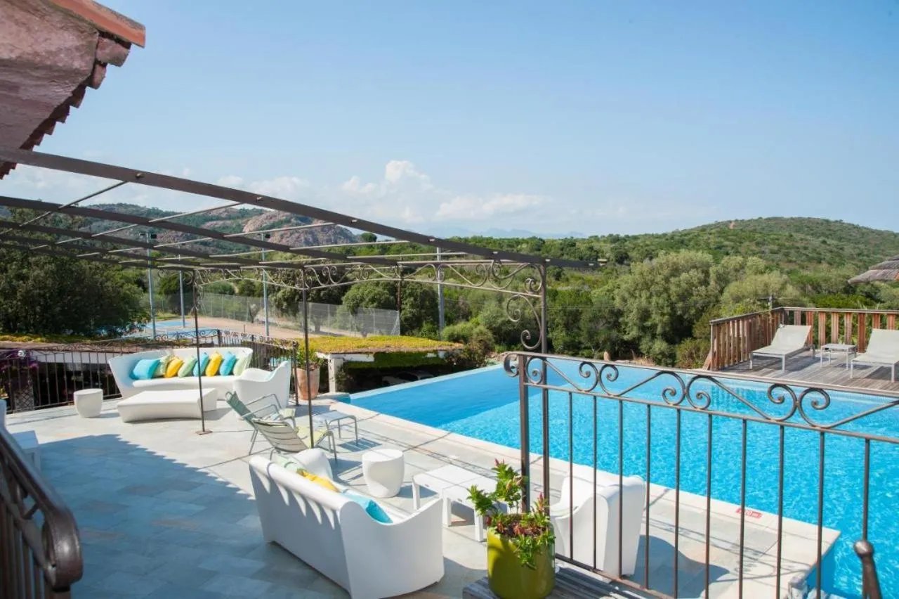 Terrasse avec salon blanc et piscine bleue surplombant un paysage verdoyant.