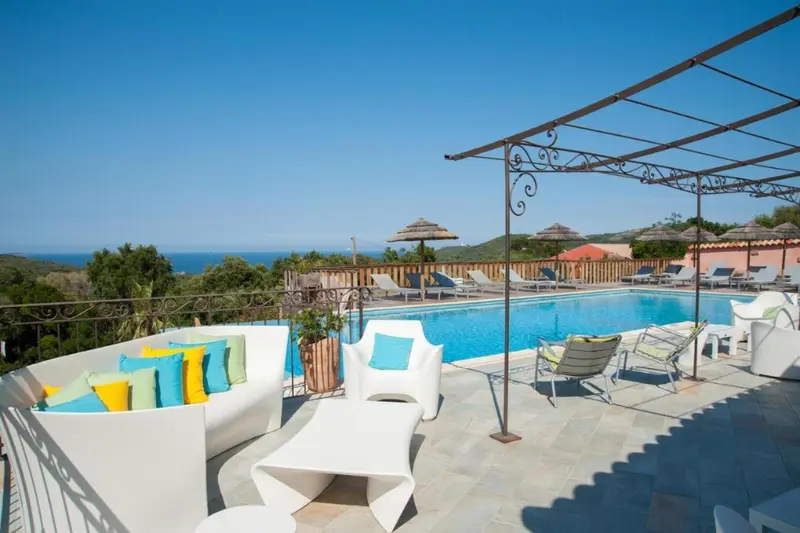 Terrasse aménagée avec salon extérieur et piscine au bord d'une végétation luxuriante.