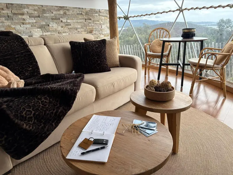 Un espace de détente intérieur avec canapé, table basse et vue sur un paysage montagneux.