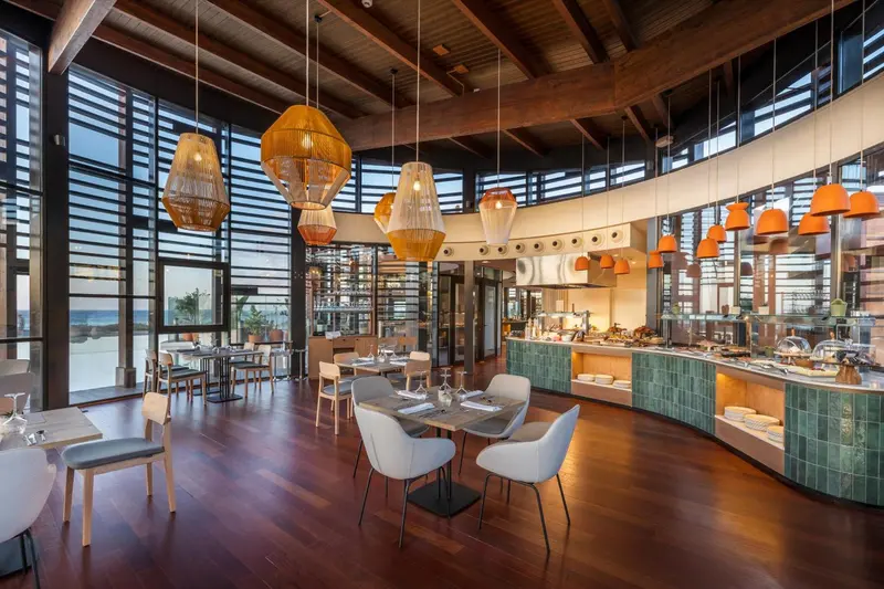 Une salle de restaurant lumineuse avec des tables dressées et un buffet.