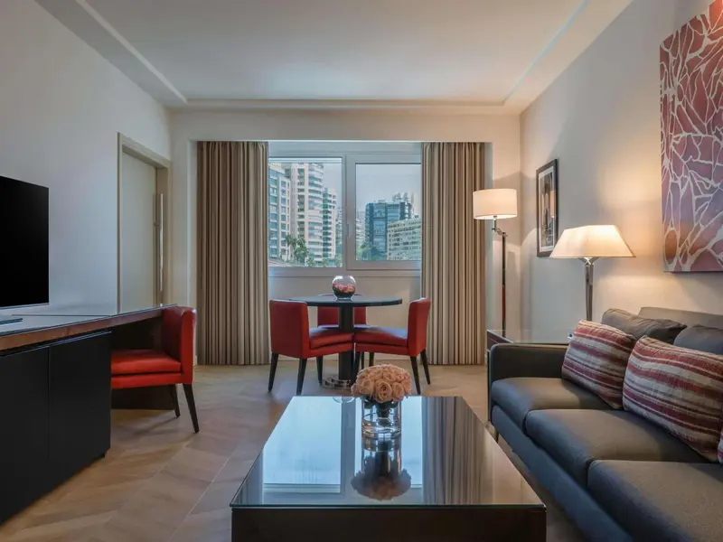 Un salon moderne avec canapé, table basse et coin repas près d'une fenêtre.