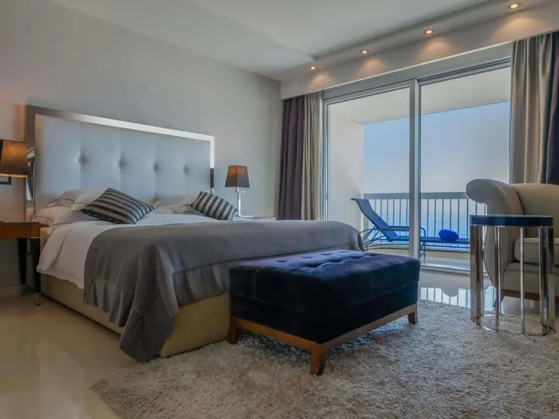 Une chambre lumineuse avec un grand lit et un accès à un balcon.