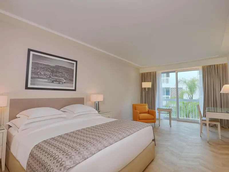 Une chambre lumineuse avec un grand lit et un fauteuil.