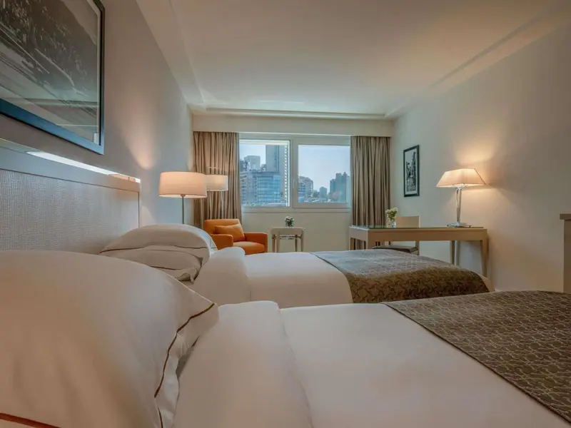 Une chambre d'hôtel lumineuse avec un grand lit et un fauteuil.