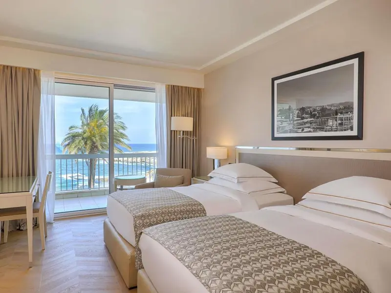 Une chambre lumineuse avec vue sur la mer depuis un balcon.