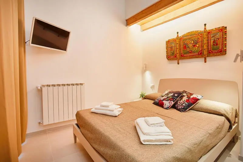 Une chambre lumineuse avec un grand lit et une télévision murale.
