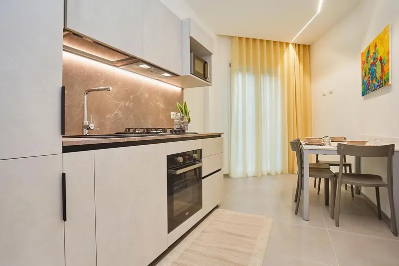 Une cuisine moderne s'ouvre sur un coin repas avec table et chaises.