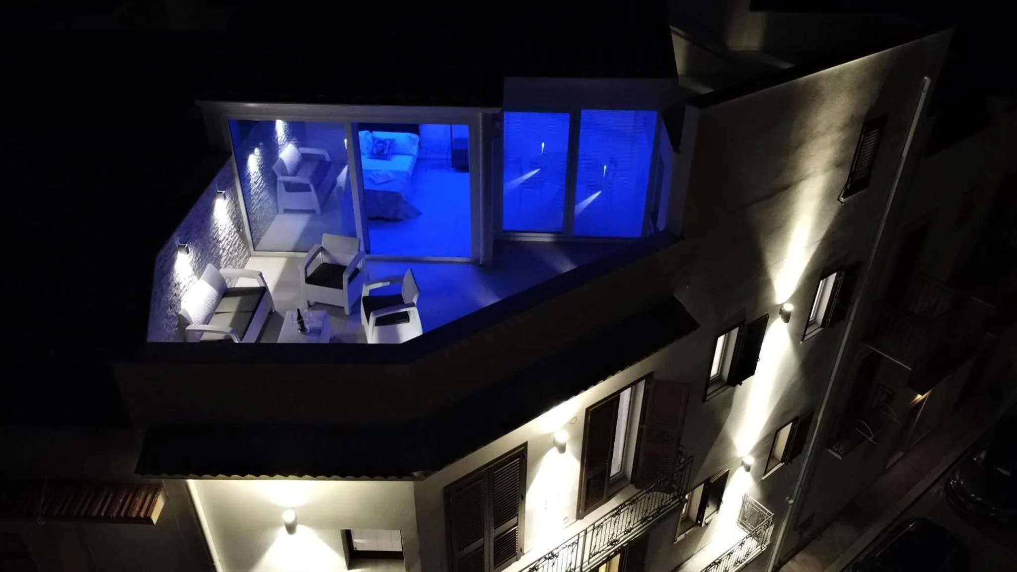 Terrasse avec mobilier d'extérieur et piscine éclairée la nuit.