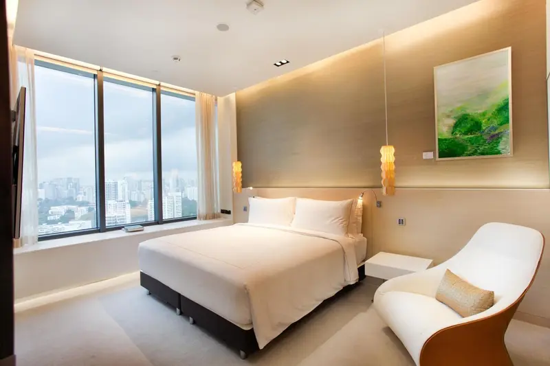Chambre lumineuse avec un grand lit et une vue sur la ville.