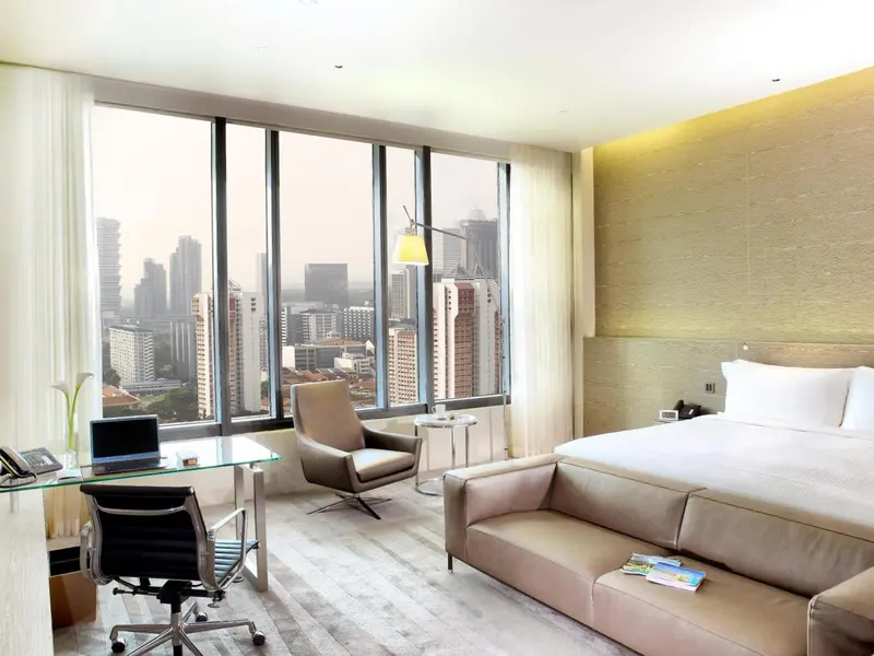 Chambre moderne avec canapé, bureau et vue sur la ville.