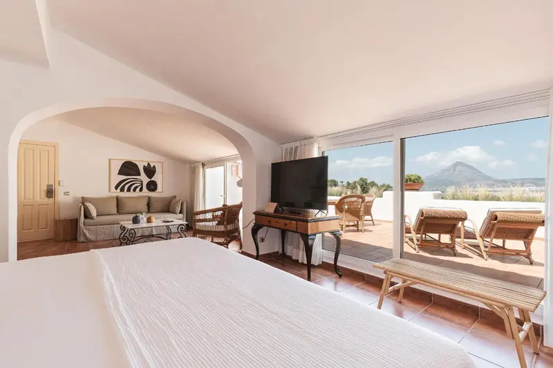 Une chambre lumineuse s'ouvre sur une terrasse avec vue sur la mer.