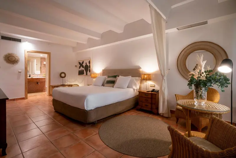 Chambre lumineuse avec un grand lit et une décoration naturelle.