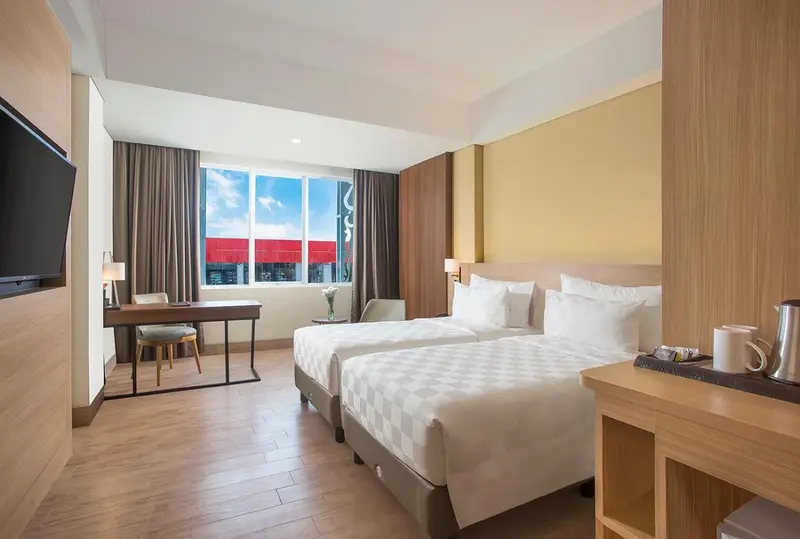 Une chambre lumineuse avec deux lits simples et un bureau.