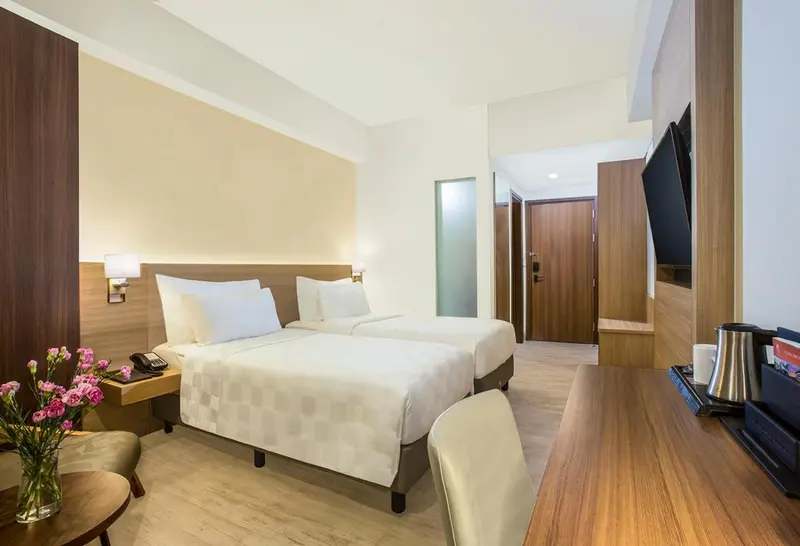 Chambre lumineuse avec un lit double et un bureau.