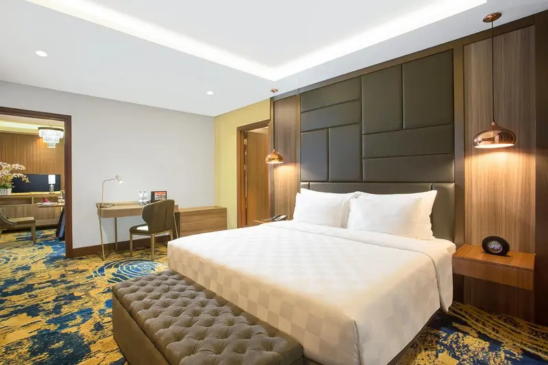 Chambre lumineuse avec un grand lit et un espace bureau.