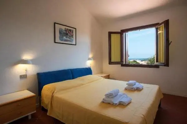 Une chambre lumineuse avec un lit fait et une fenêtre ouverte sur le paysage.