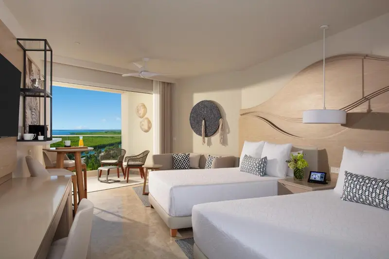 Une chambre lumineuse avec un lit double et un coin salon donnant sur une vue dégagée.