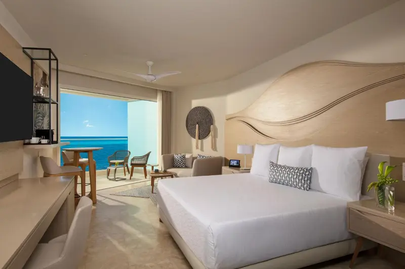 Chambre lumineuse avec un grand lit et une vue sur la mer.