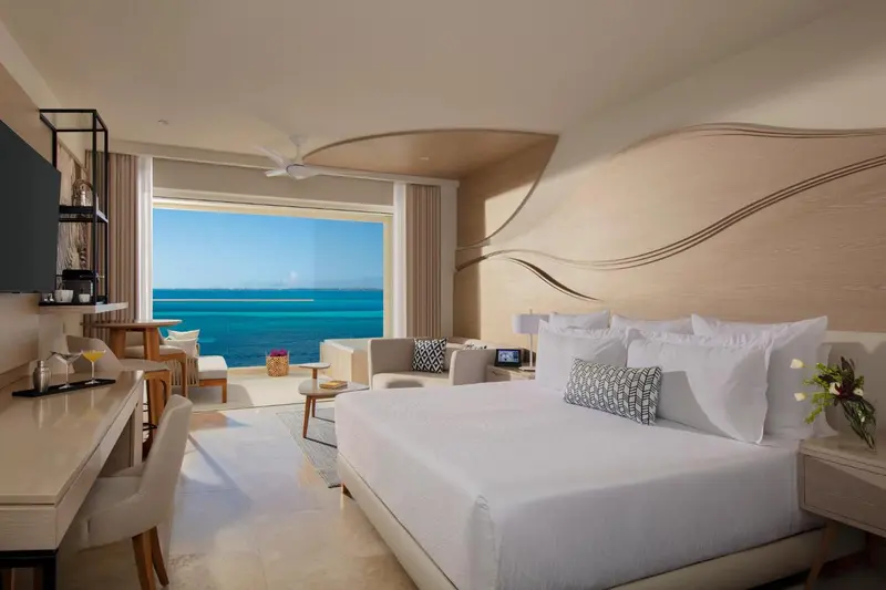 Chambre lumineuse avec un grand lit et vue sur la mer.