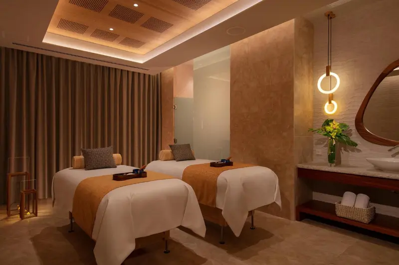 Deux lits de massage sont préparés dans une salle aux tons chauds.