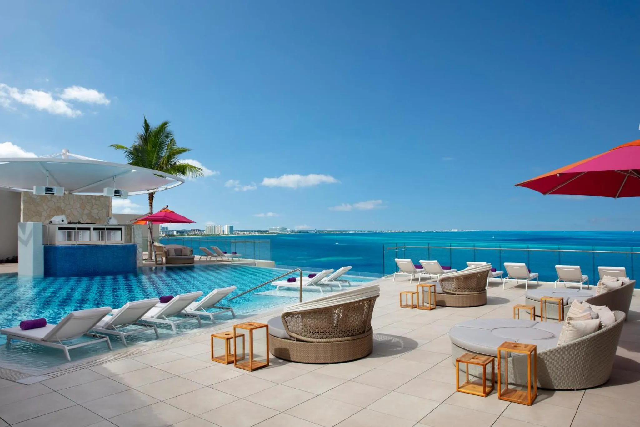 Terrasse avec transats et piscine à débordement donnant sur la mer.