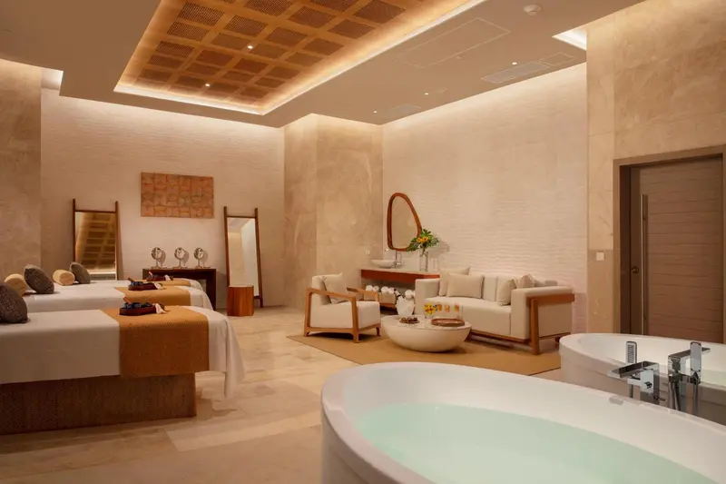 Espace de détente intérieur avec lits de massage et baignoire.