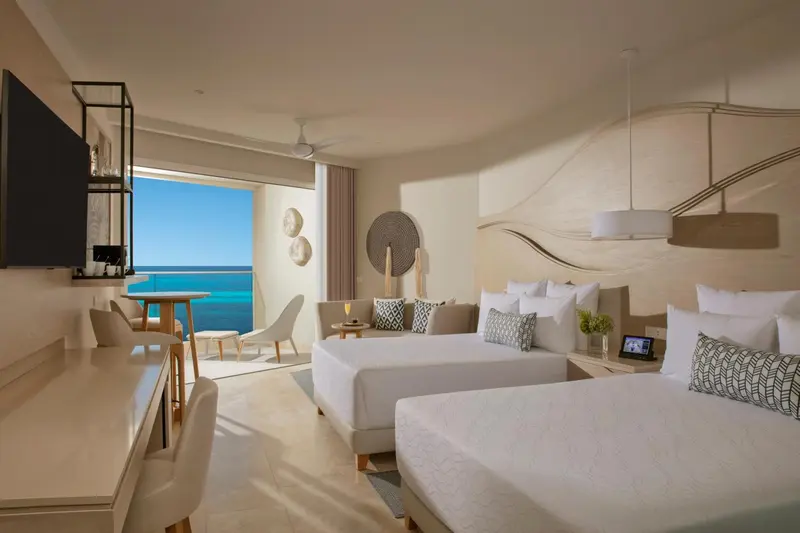 Chambre lumineuse avec vue sur la mer et mobilier clair.