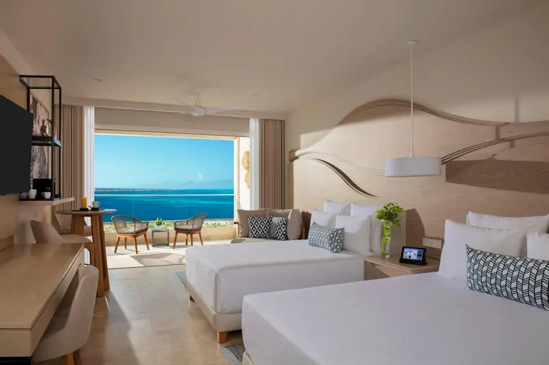 Chambre lumineuse avec vue sur la mer depuis un grand balcon.