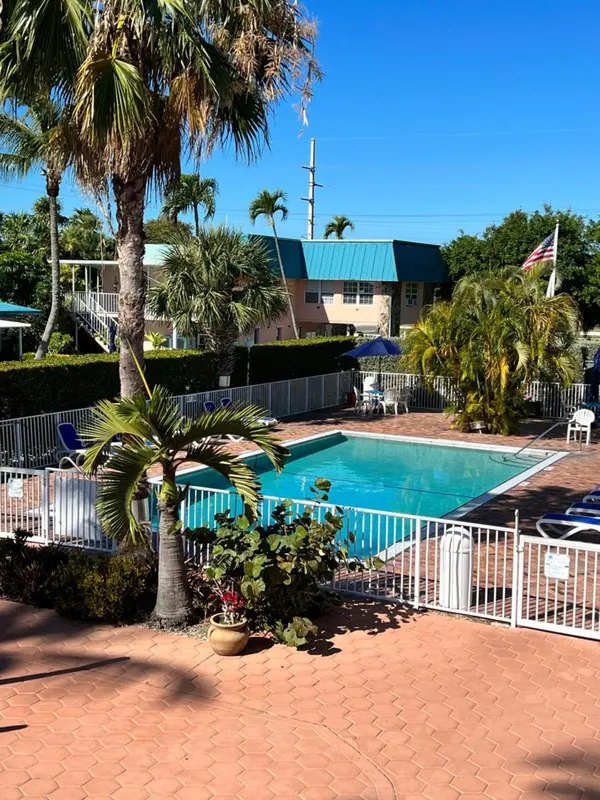 Une piscine rectangulaire entourée d'une terrasse et de végétation tropicale.