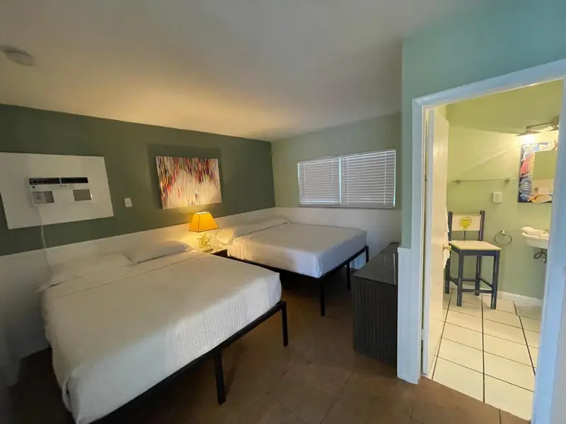 Une chambre lumineuse avec deux lits simples et un accès à une salle de bain.
