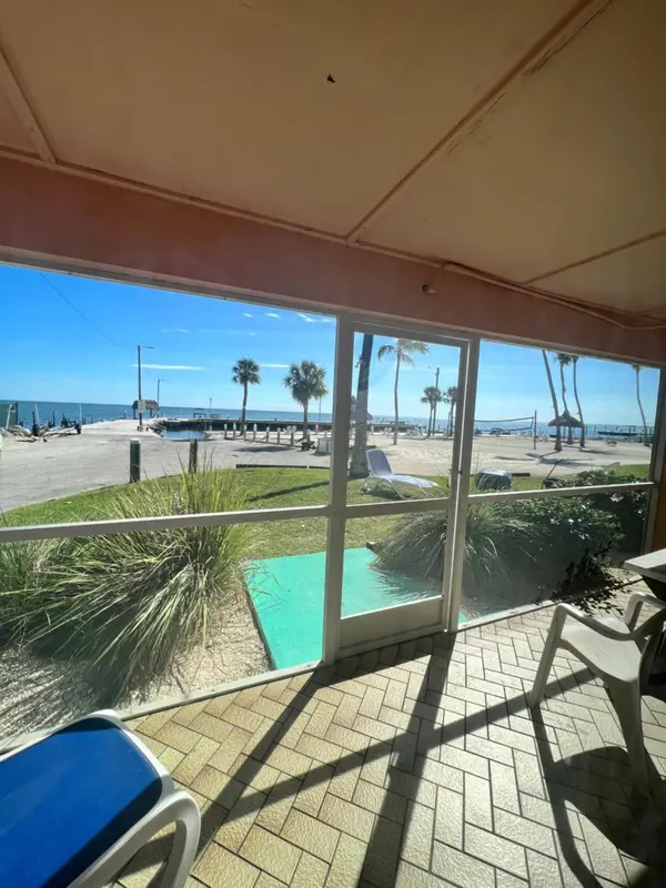 Vue sur une plage ensoleillée depuis une terrasse ombragée.