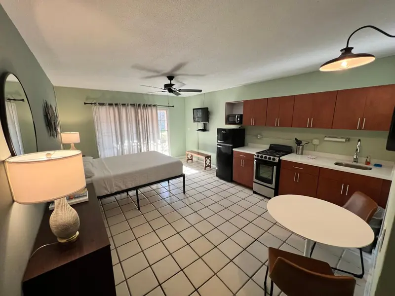 Une pièce lumineuse avec un lit, une kitchenette et une table.