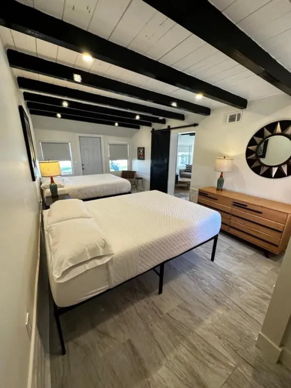 Chambre lumineuse avec deux lits simples et une commode en bois.