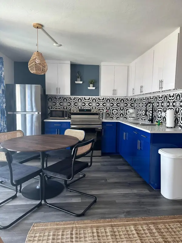 Une cuisine moderne avec des armoires bleues et blanches et une table à manger en bois.