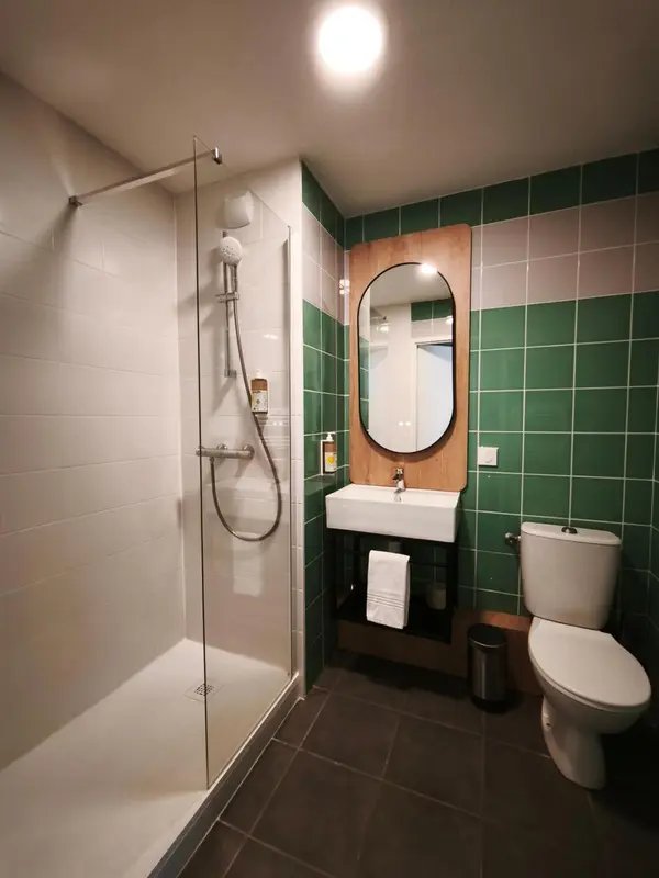 Une salle de bain moderne avec douche à l'italienne et carrelage vert.