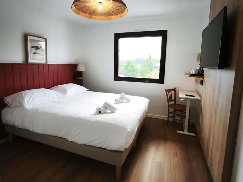 Une chambre lumineuse avec un grand lit et un bureau.