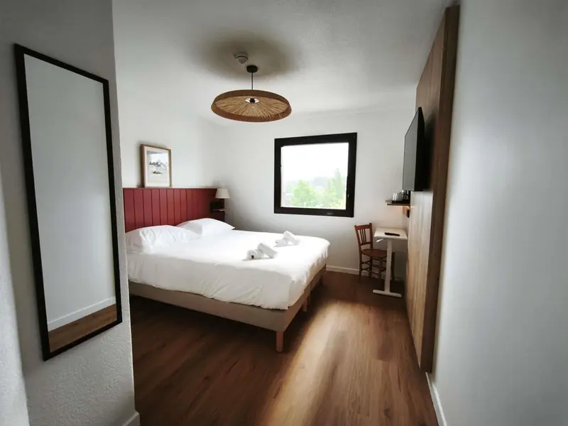Une chambre lumineuse avec un lit double et un bureau.