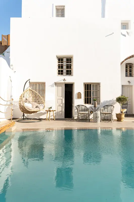 Terrasse avec mobilier d'extérieur et piscine turquoise au premier plan.