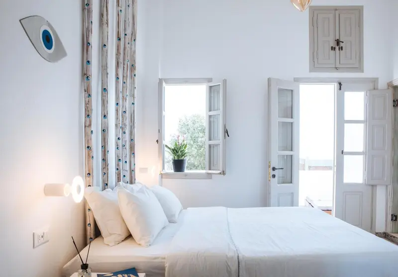 Une chambre lumineuse avec un grand lit blanc et des rideaux décoratifs.