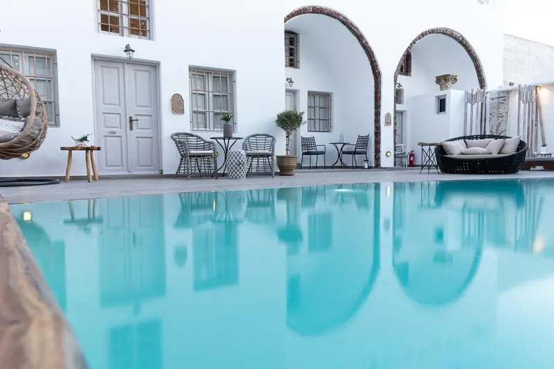 Terrasse avec mobilier d'extérieur et piscine turquoise reflétant l'architecture.