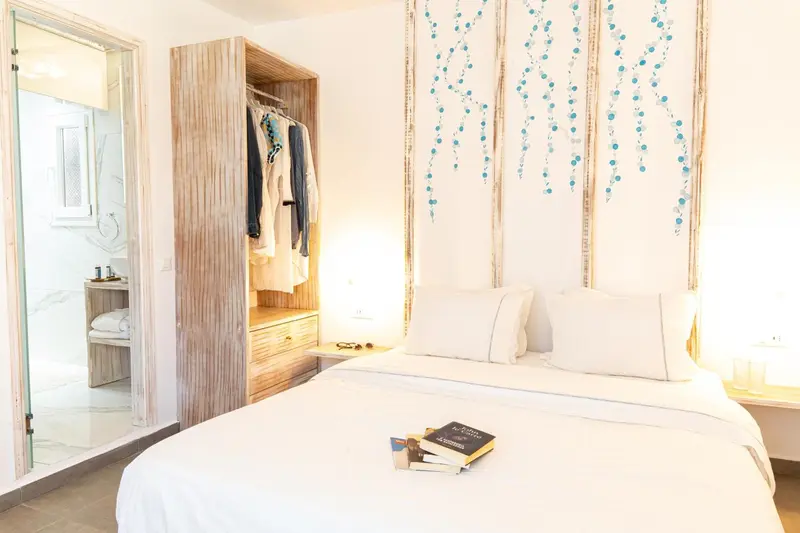 Une chambre lumineuse avec un grand lit et un placard ouvert.