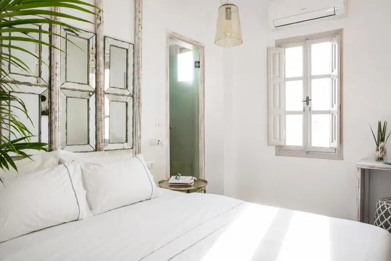 Une chambre lumineuse avec un lit blanc et des éléments décoratifs muraux.