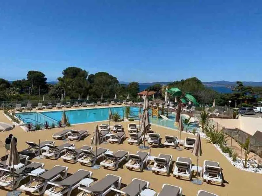 Transats et parasols bordent une piscine ensoleillée avec vue sur la mer.