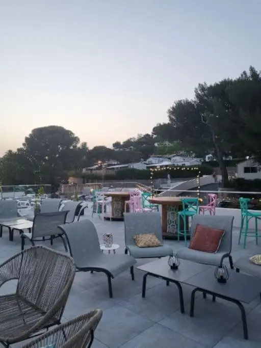 Terrasse aménagée avec des tables et des chaises, éclairée par des guirlandes lumineuses.